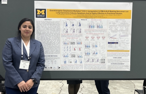 Dr. Ananya Banerjee standing in front of poster presentation for QO interactions with EML4-ALK