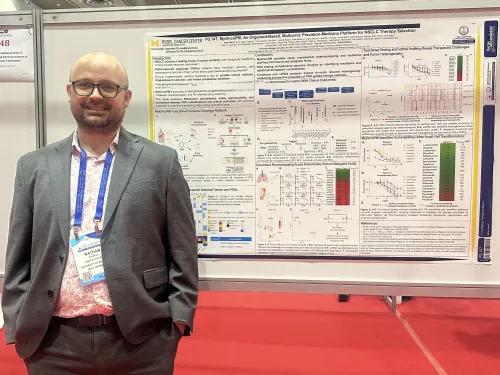 Dr. Nathan Merrill in front of poster
