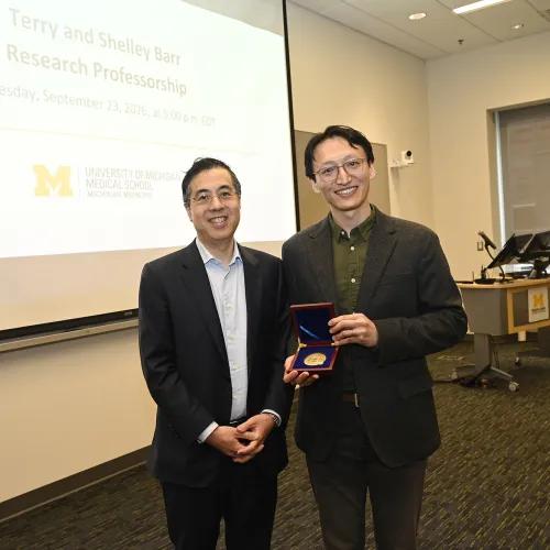 Dean Thomas Wang presents a medallion on behalf of the U-M Board of Regents to Yunlu Zhu