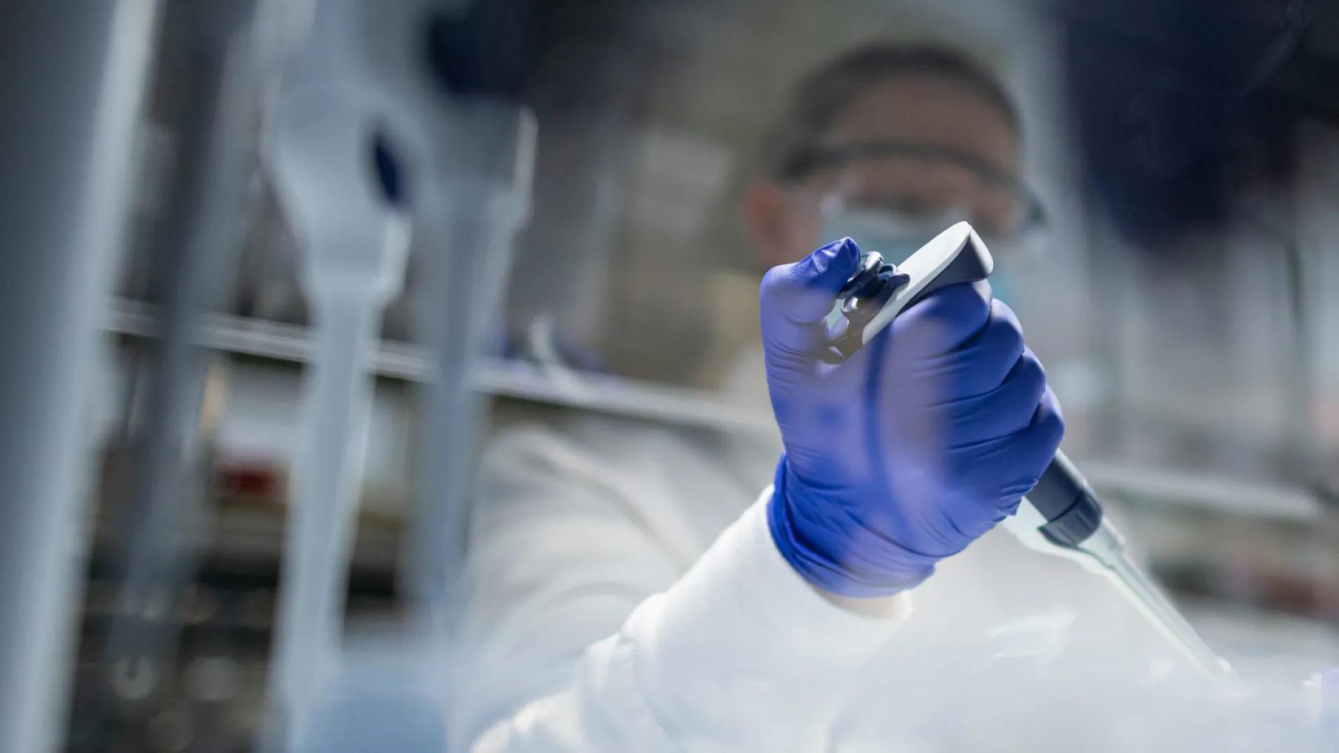 faded image of researcher in lab using pipette