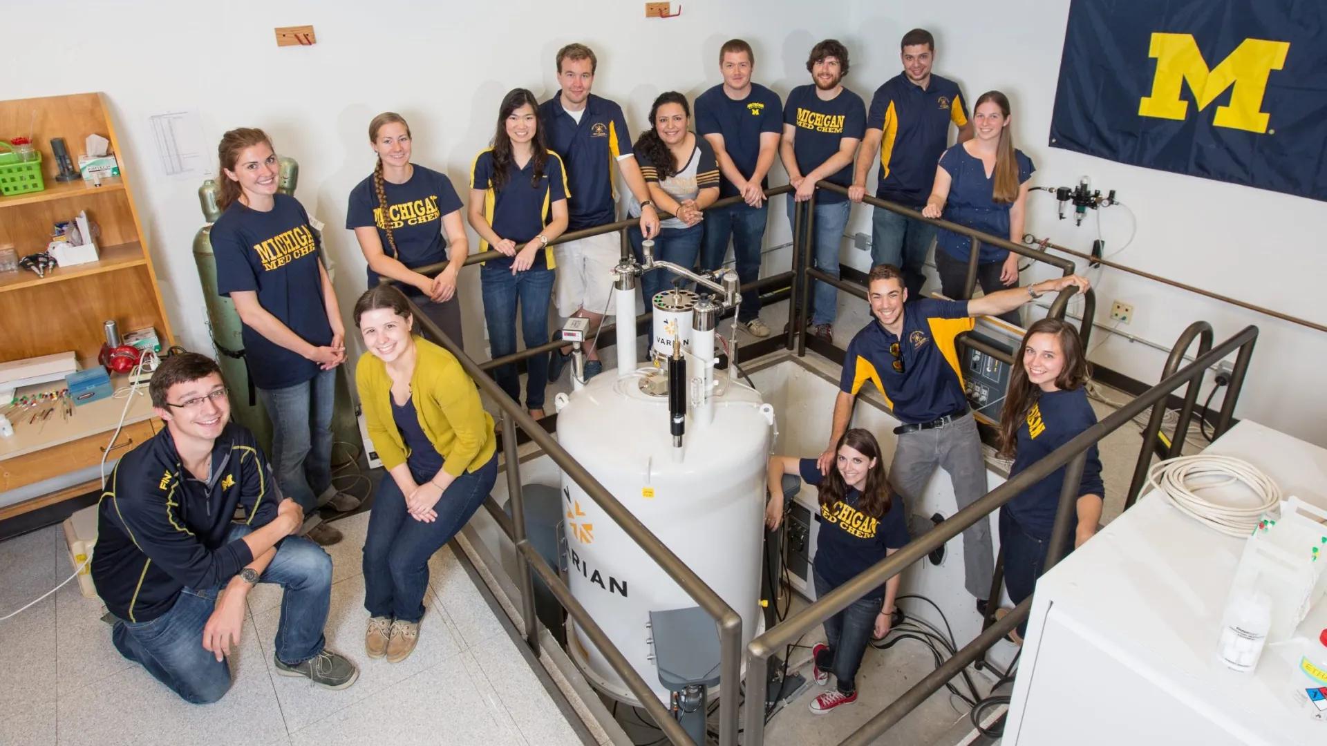 multiple people gathered together posing for group photo, wearing University of Michigan clothes