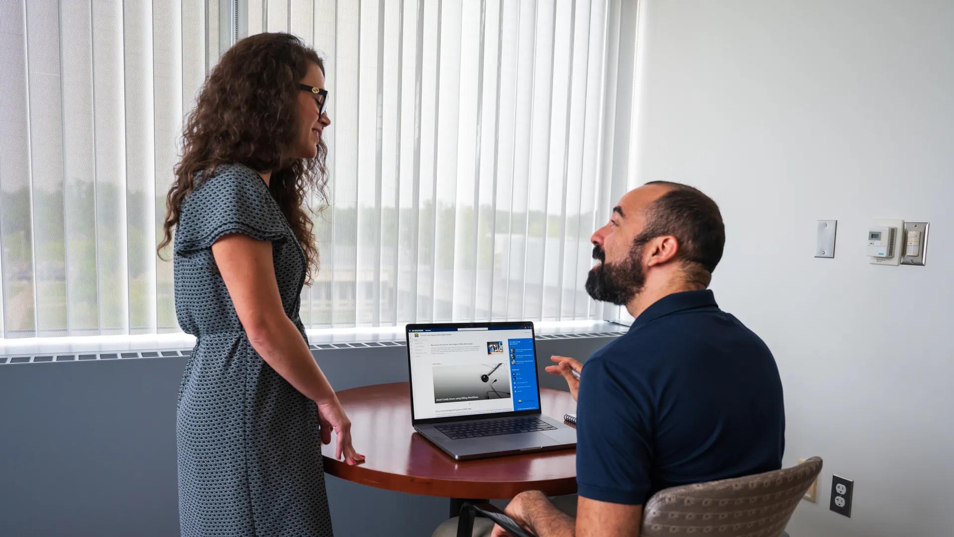 Photo of a man and woman sitting in front of a computer that is open to CTMS sharepoint