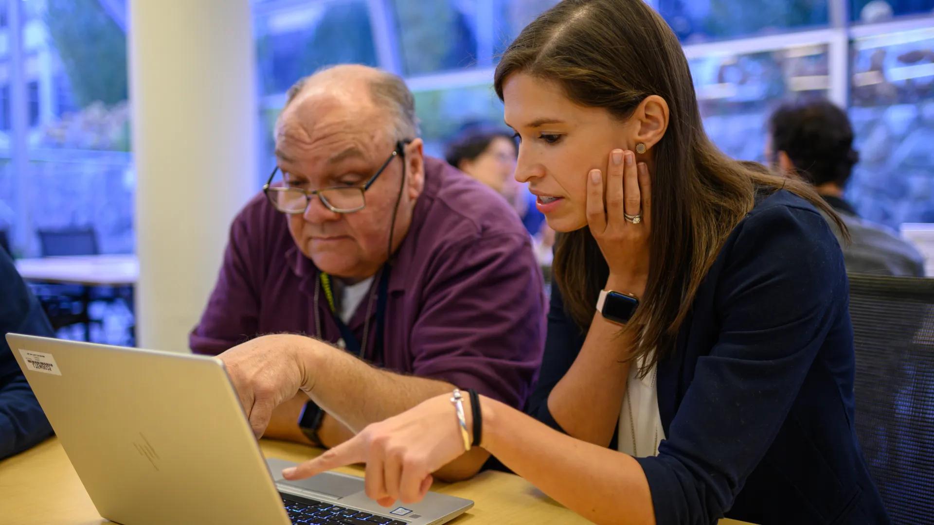 Photo of a man and woman in front of a laptop computer pointing 