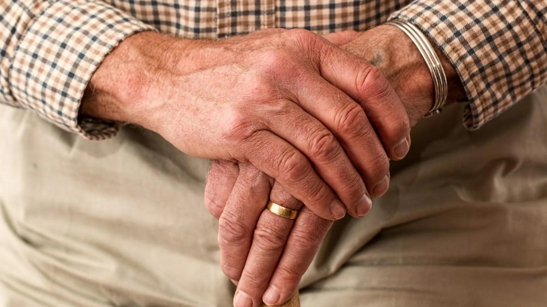 An older man's hands with a gold wedding band on the left hand