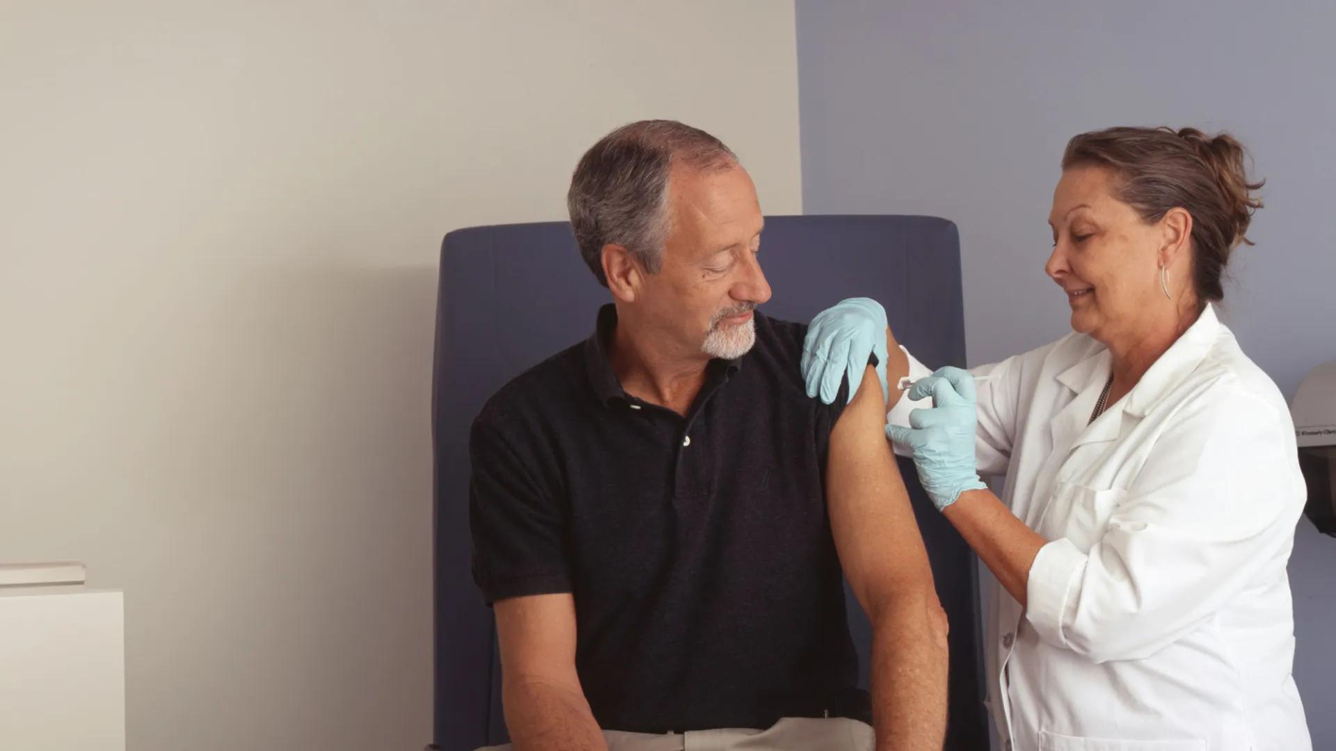Nurse gives silver-haired gentleman a shot in the arm