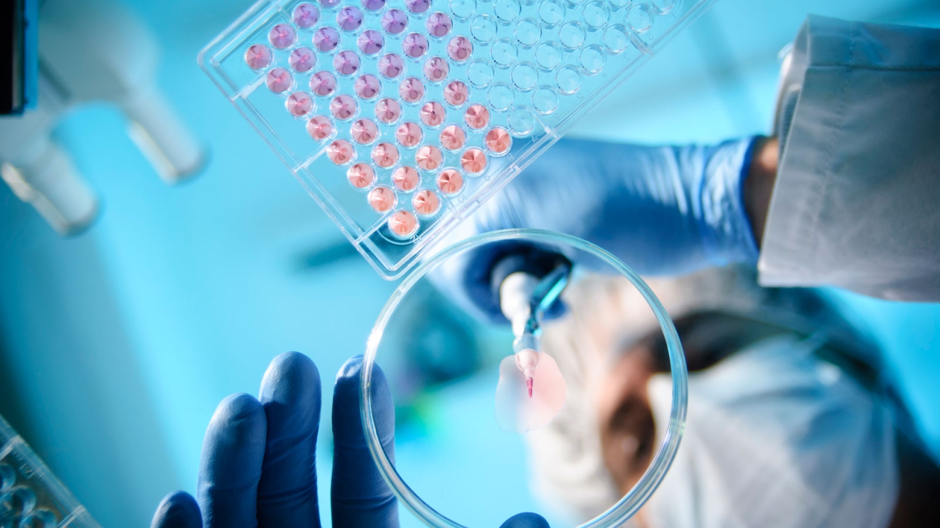 A masked researcher pipetting in a lab