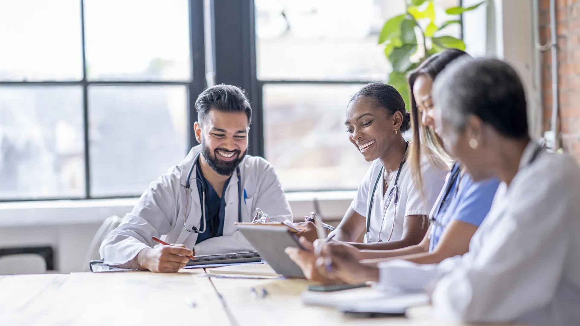 four medical personnel sitting around a table smiling