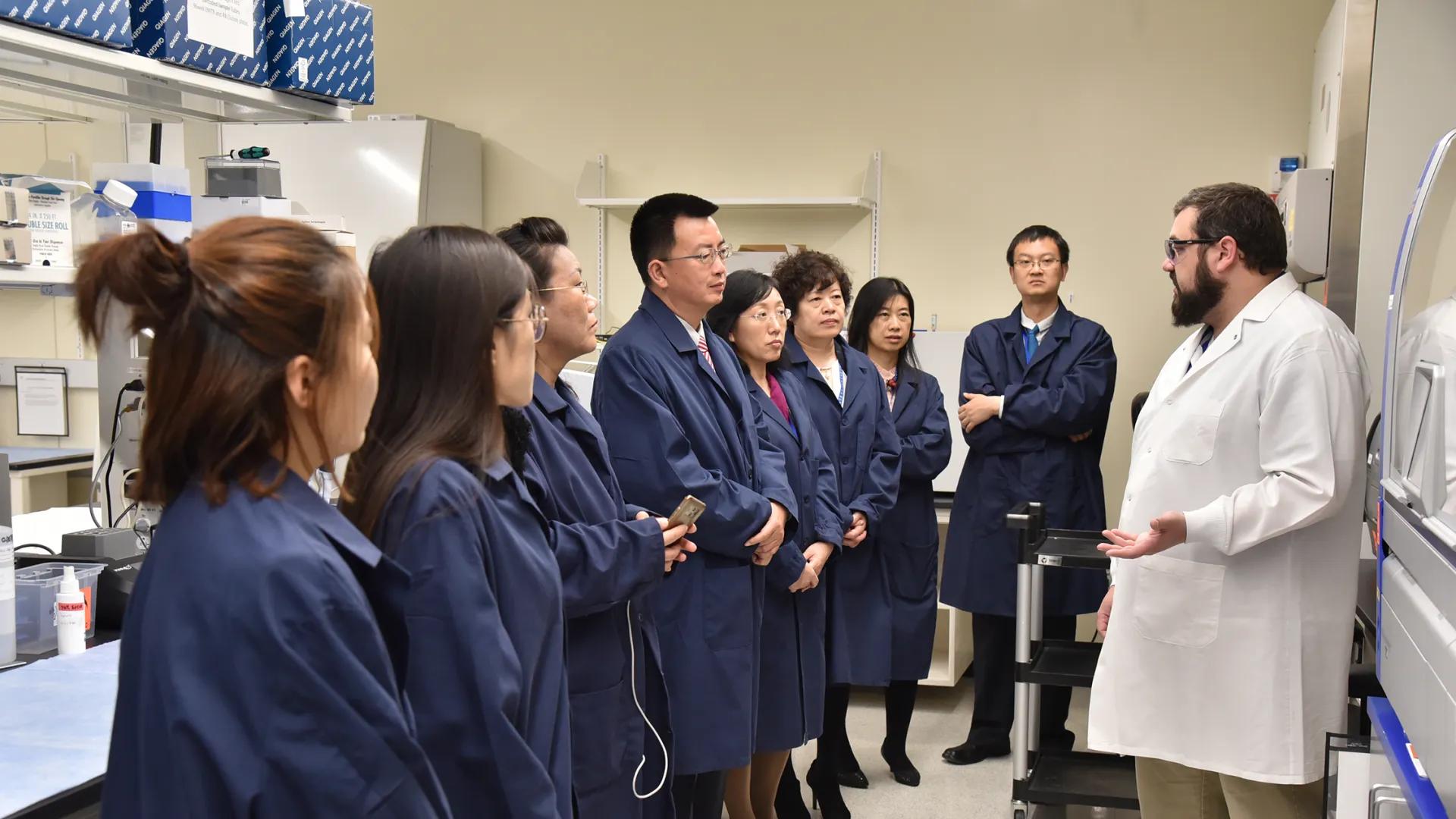 group of people in lab listening to man in white coat