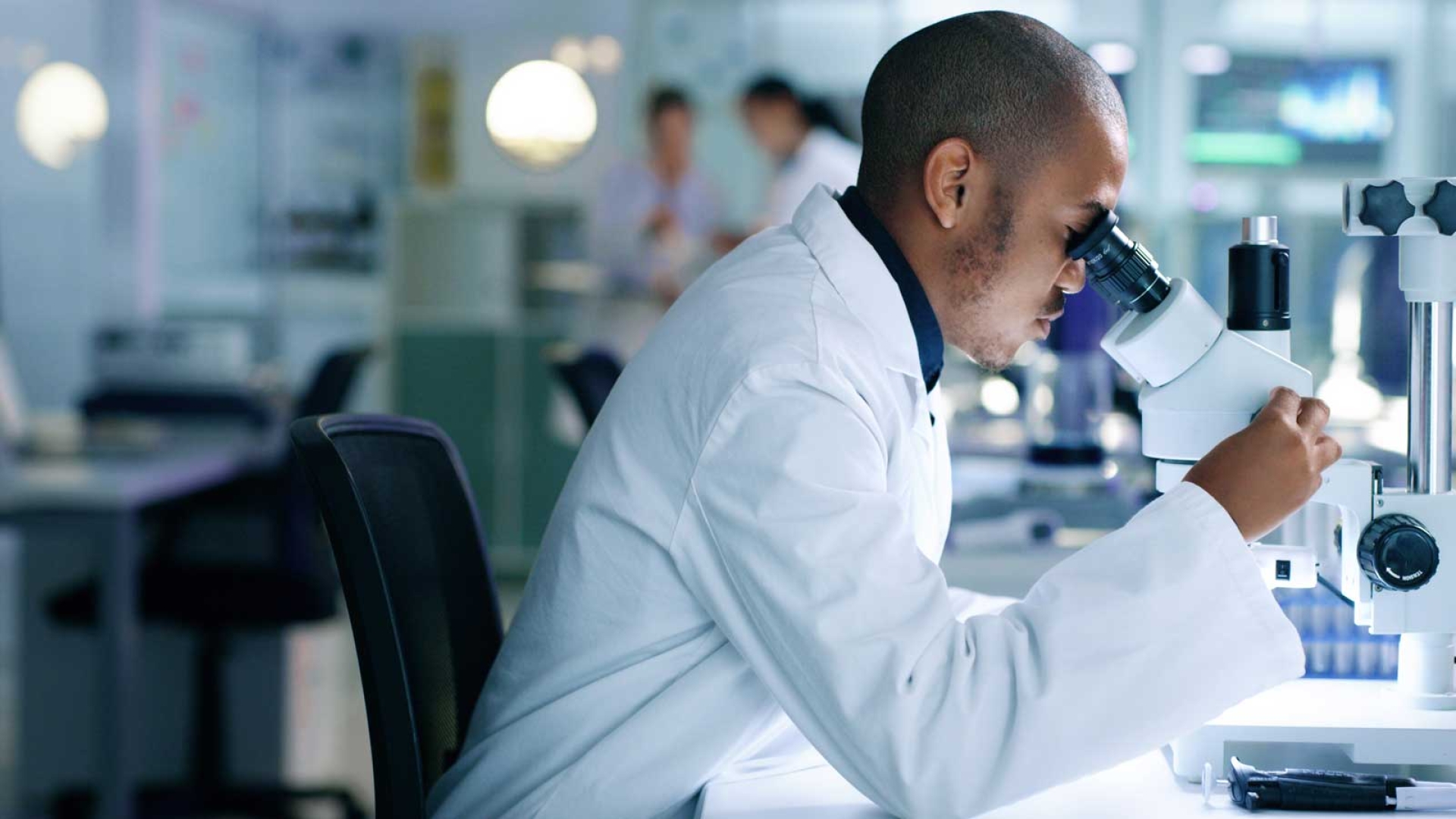Scientist in a lab looking into a microscope