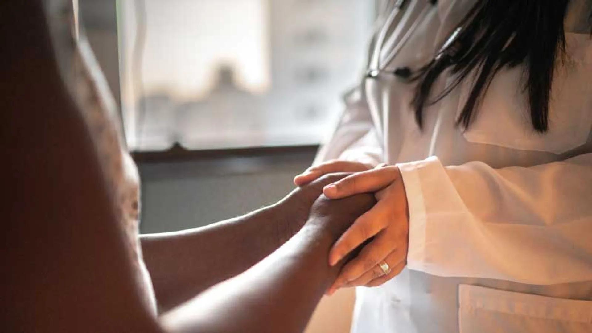 Physician holding the hands of someone about to receive a screening
