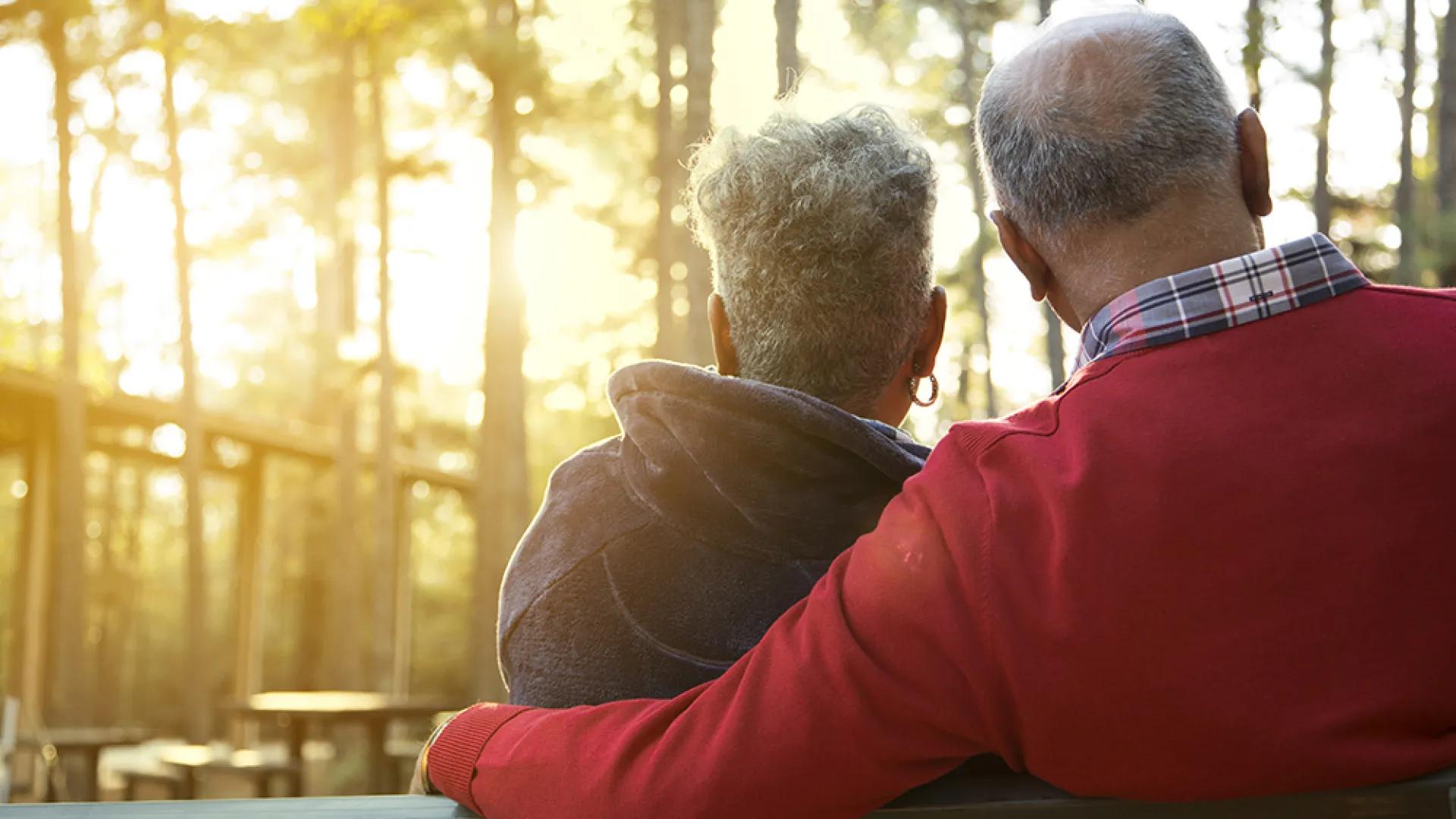 man and woman sitting on a bench at sunset