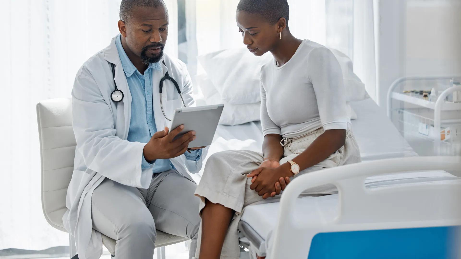 Doctor consulting patient with digital tablet, discussing diagnosis and medical checkup in hospital