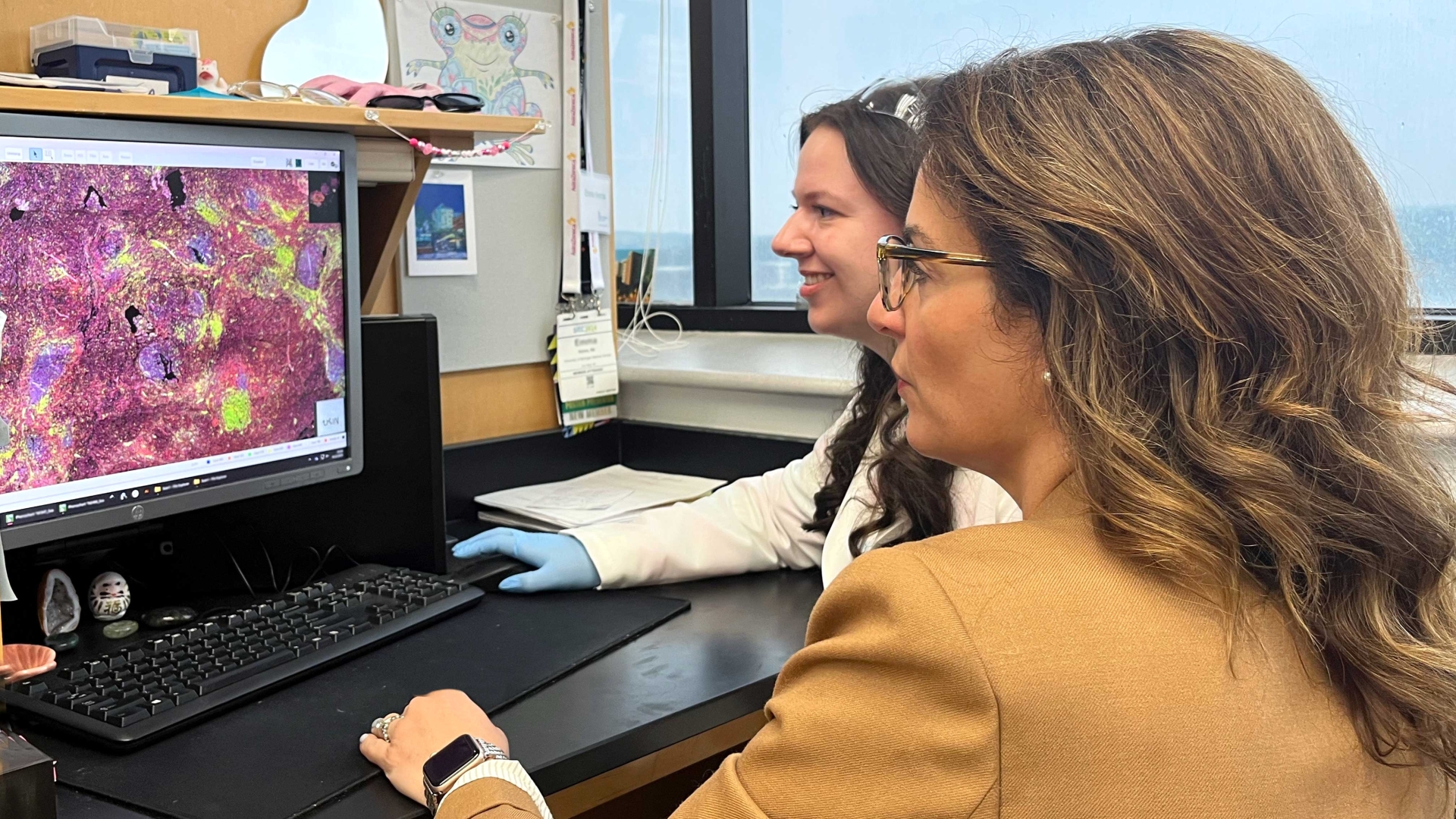 Dr. Angeles and lab member looking at computer in the lab