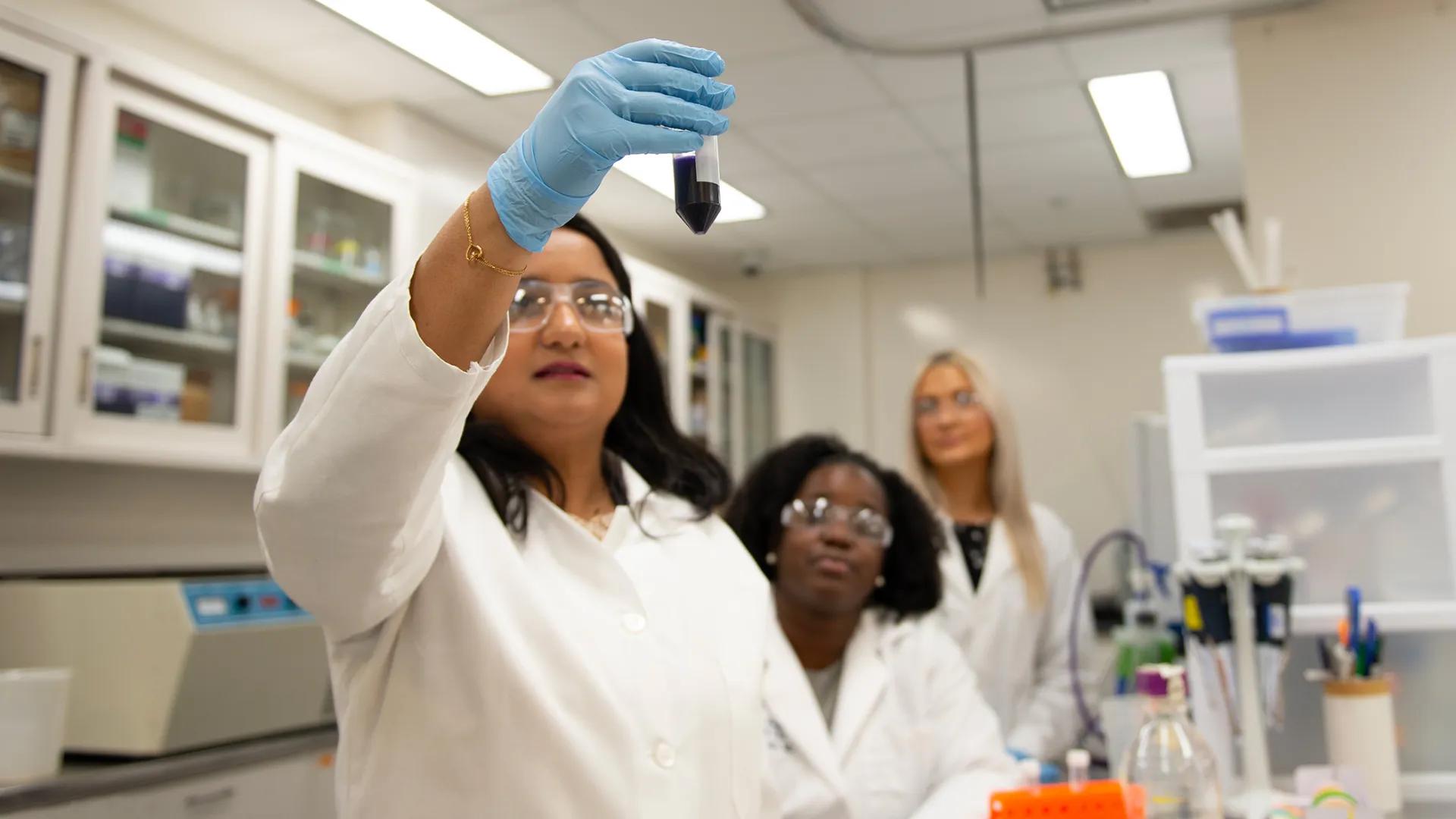 Team members looking at a test tube in the lab