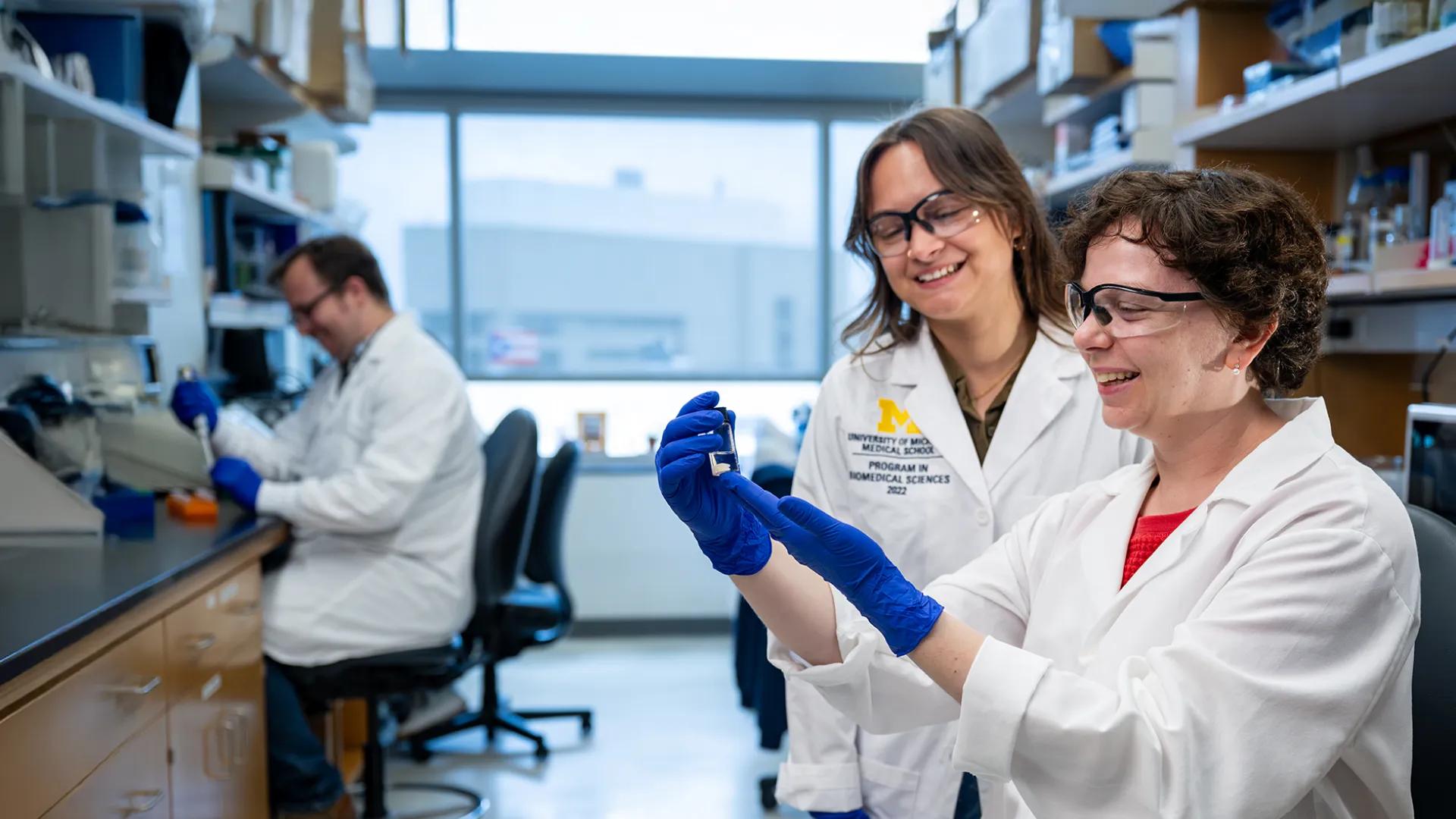 three researchers working in a lab and smiling