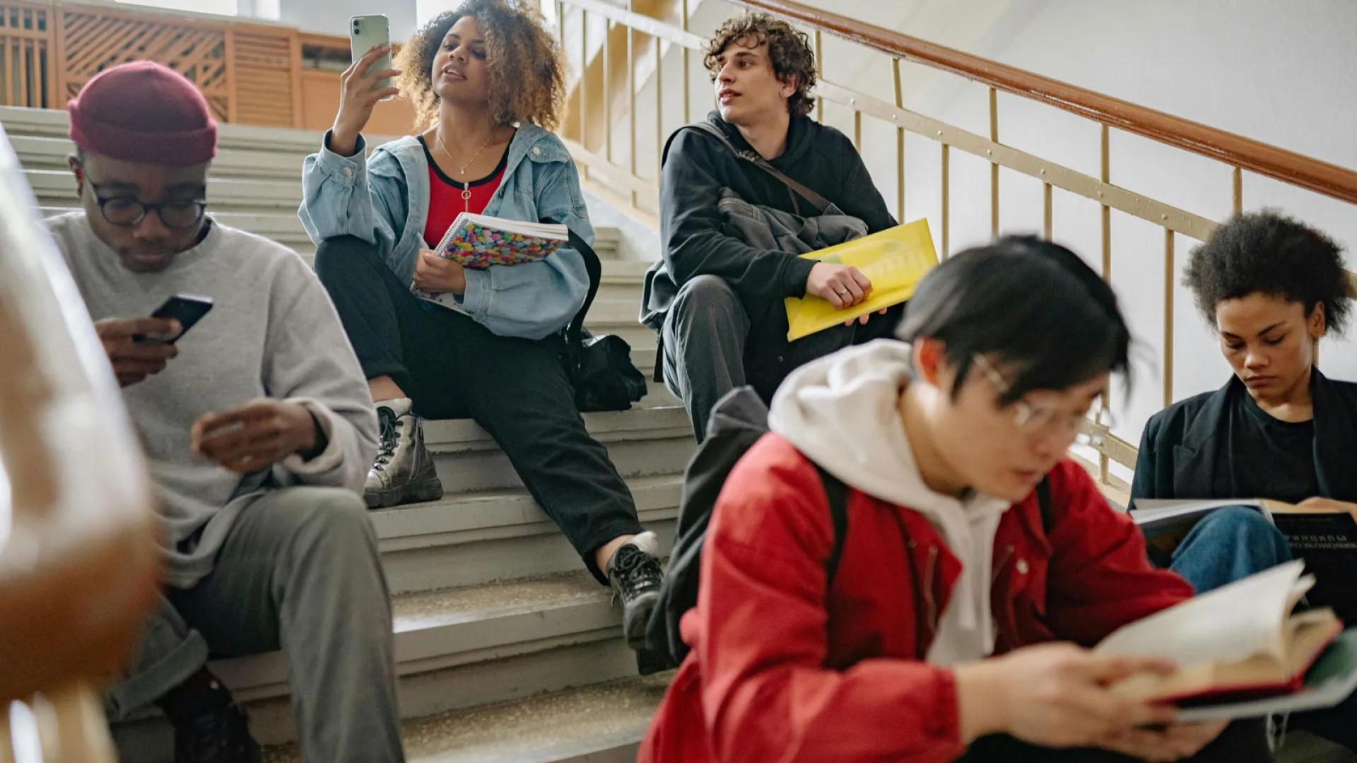 School age students sit on stairs reading and socializing.