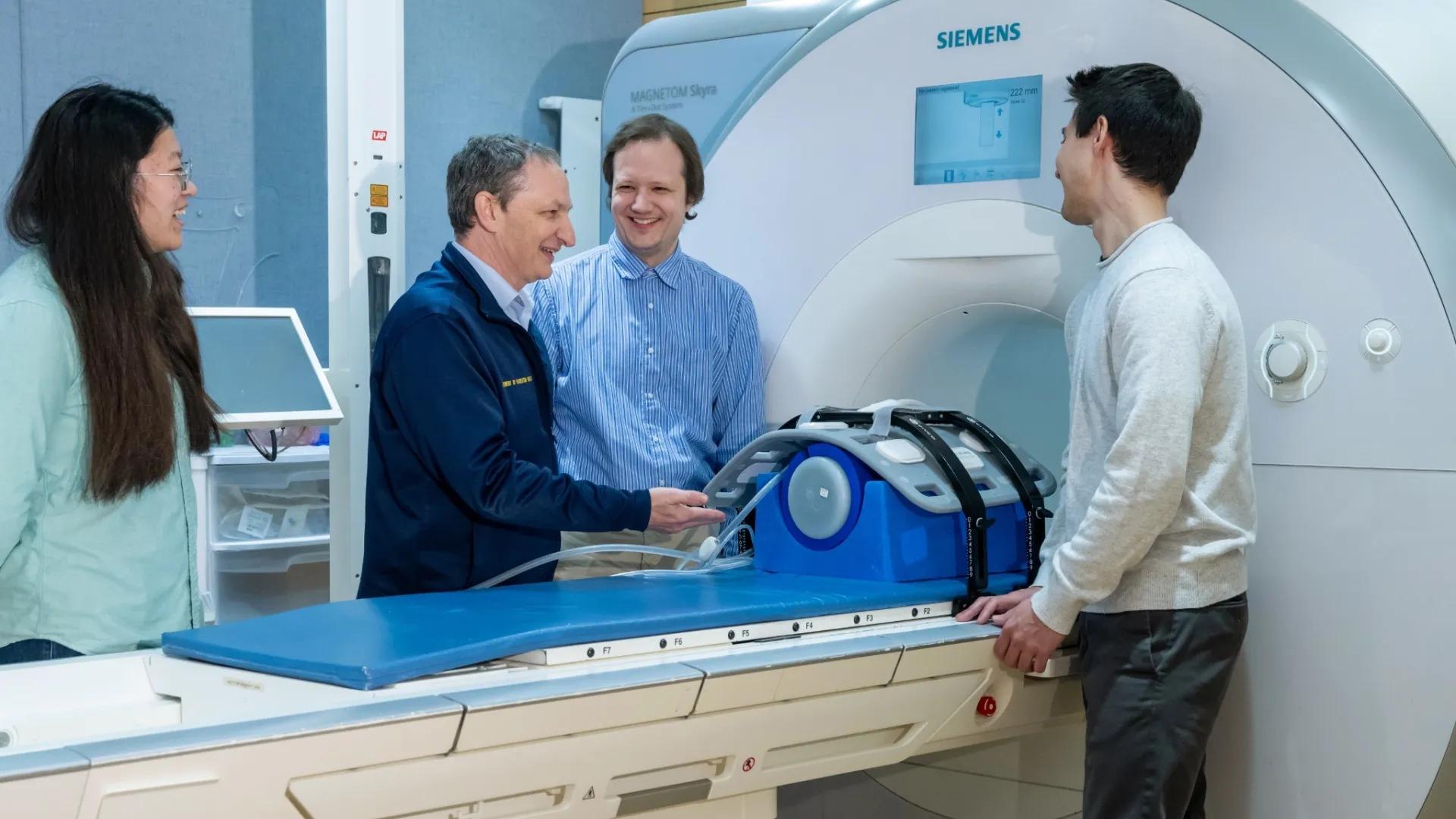 Four people gather around a MRI machine.