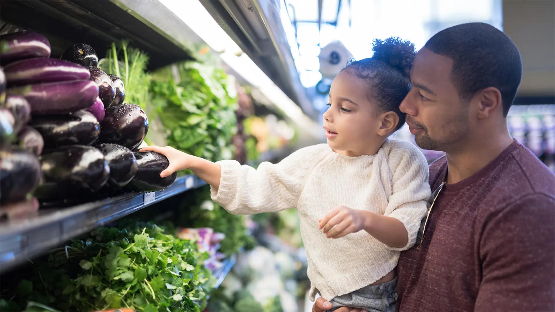 father and daughter shopping at a grocery store in the produce area