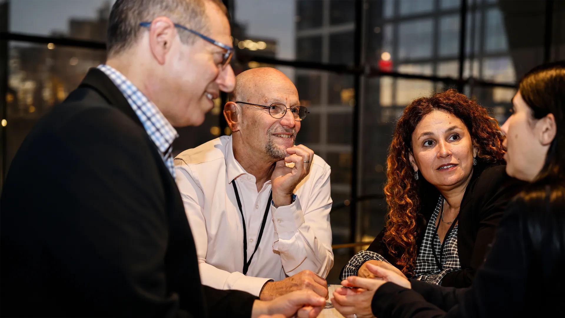 group of four people smiling and talking at an evening event