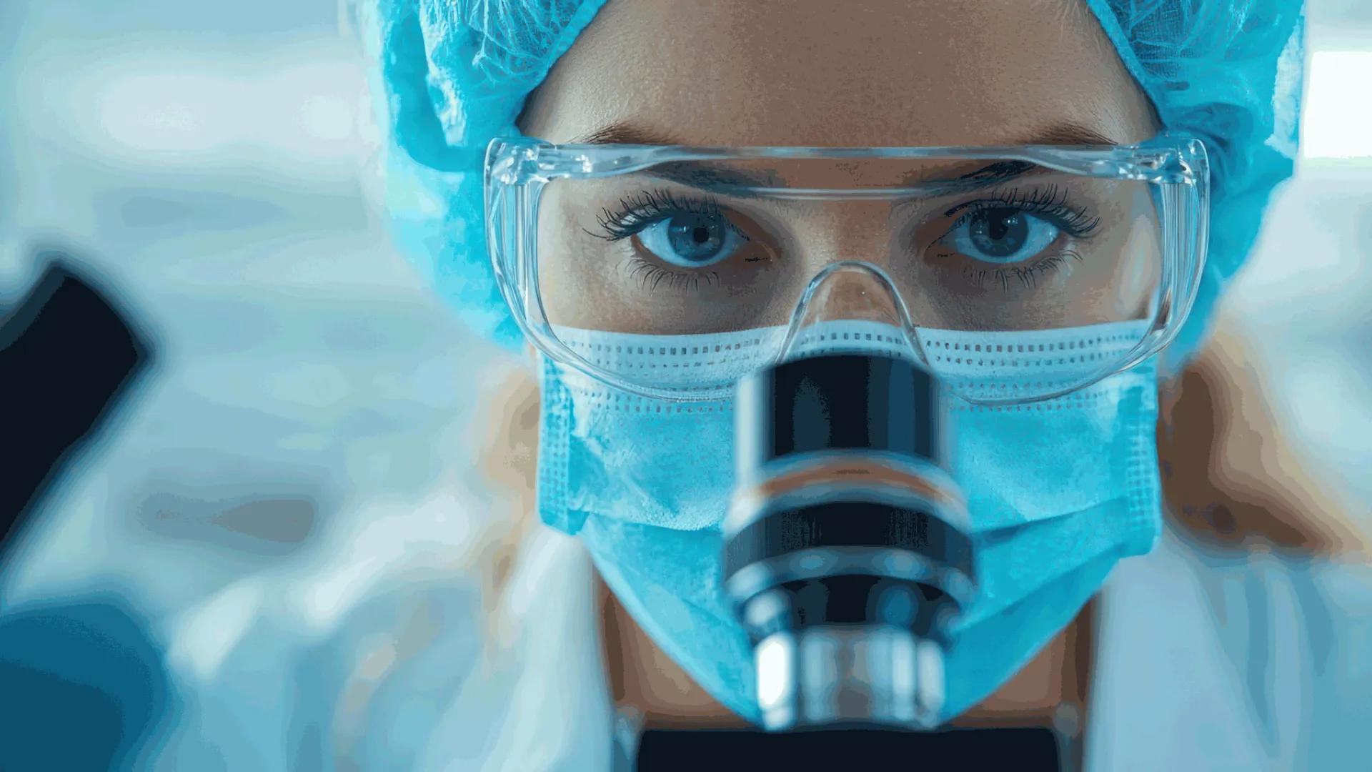 Scientist analyzing biopsy slides under a microscope