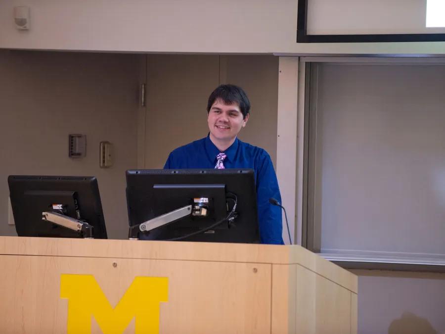 male student standing at a podium giving a presentation