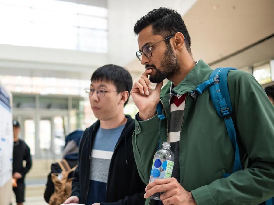 two students gather to read a poster