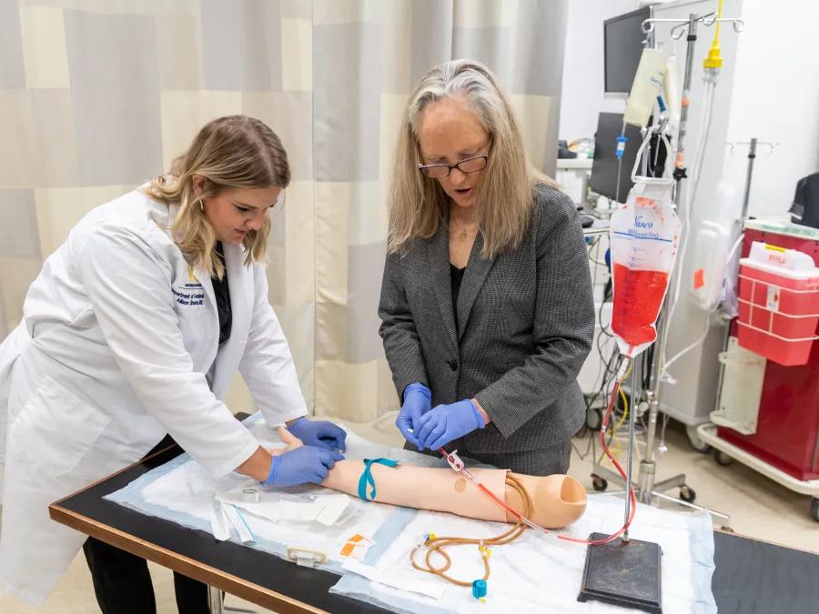 full view of doctor and trainee practicing injections into the arm 
