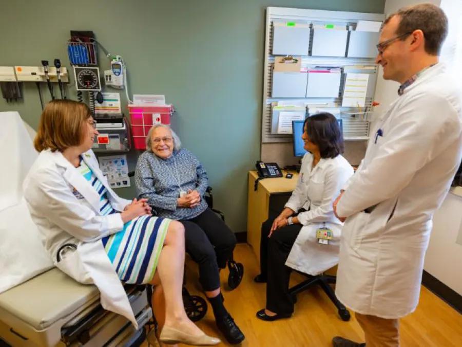 Providers speak with a patient in an exam room