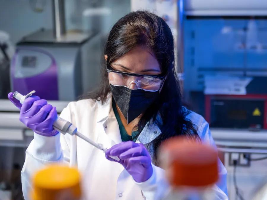 Resident working the lab using a pipette 