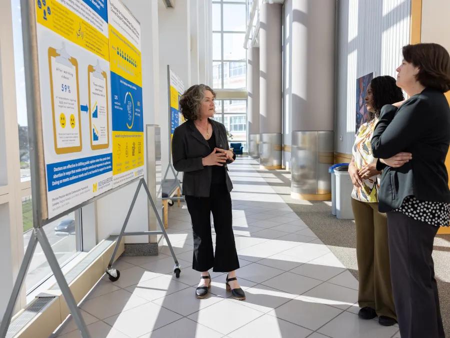 a group of women standing in front of a poster
