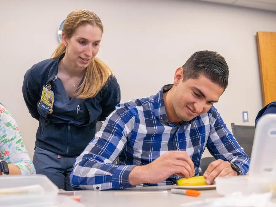 Male dermatology learner practices surgery on a banana