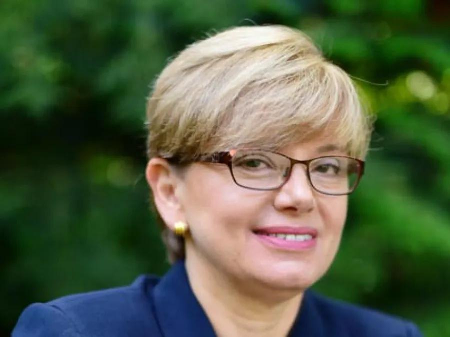 Smiling portrait of Eve Kerr wearing glasses and a blue jacket.