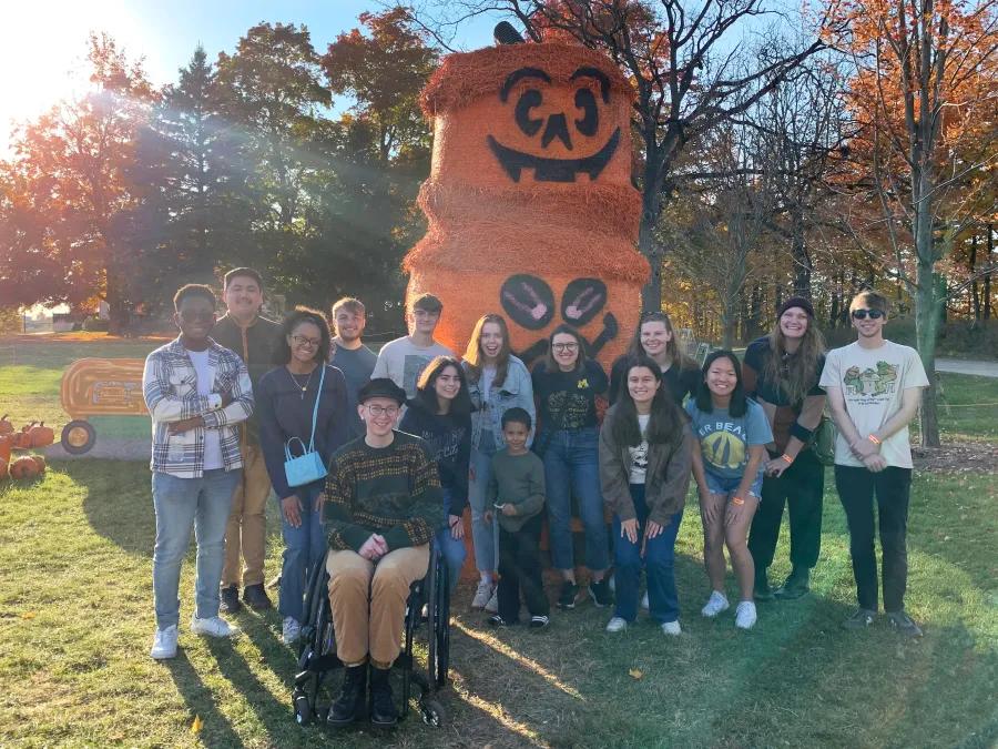 group of students posing by a pumpkin decoration