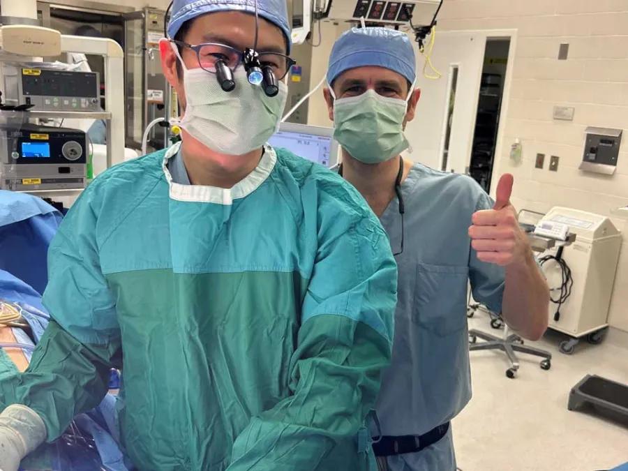 Two surgeons in operating room performing surgery gives thumbs up