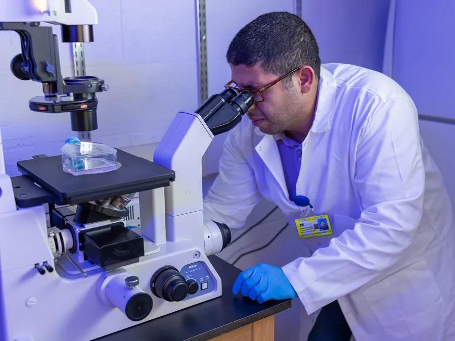 man working in a research lab looking into microscope