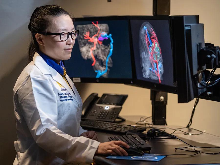 A neuroradiologist analyzing colorful brain scans on multiple monitors