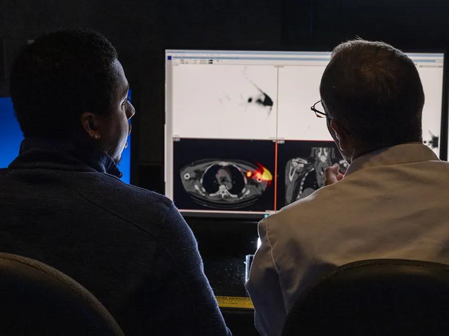 Two doctors viewing and discussing nuclear medicine imaging results on screen