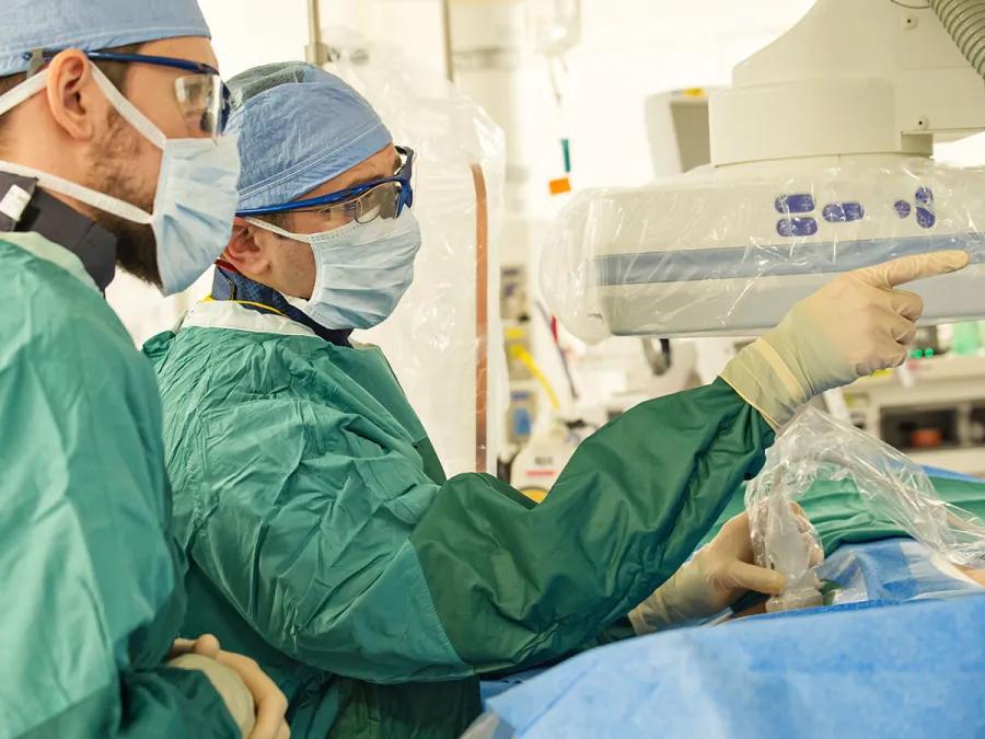Two physicians in surgical attire performing an interventional radiology procedure