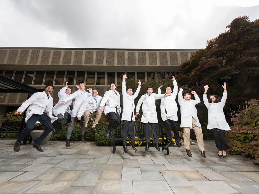 Diagnostic Radiology residents jump for a photo in their white coats
