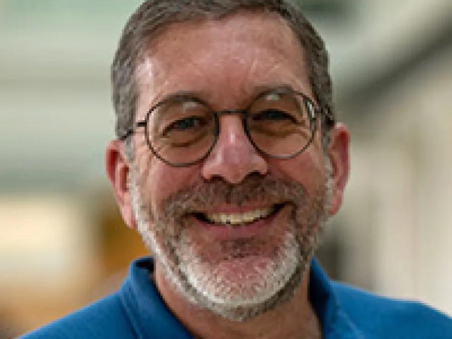 a man with a blue shirt and circle glasses