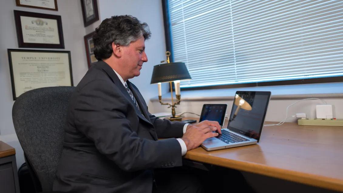 faculty member typing on computer inside office