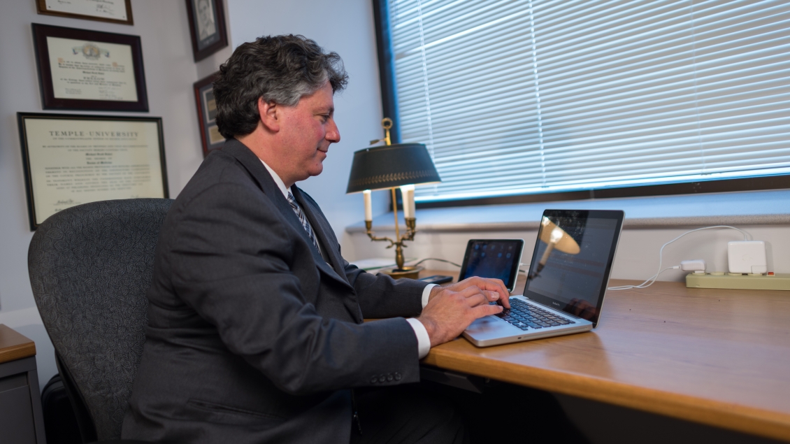 faculty member typing on computer inside office