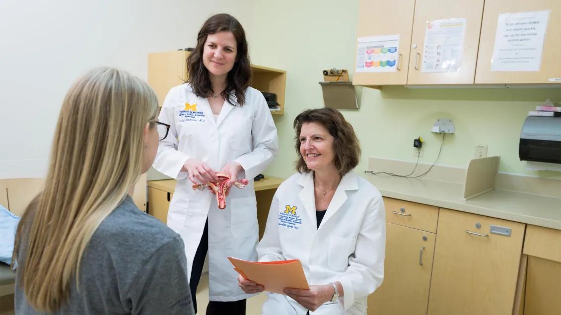  doctor stands with resident to talk to patient 