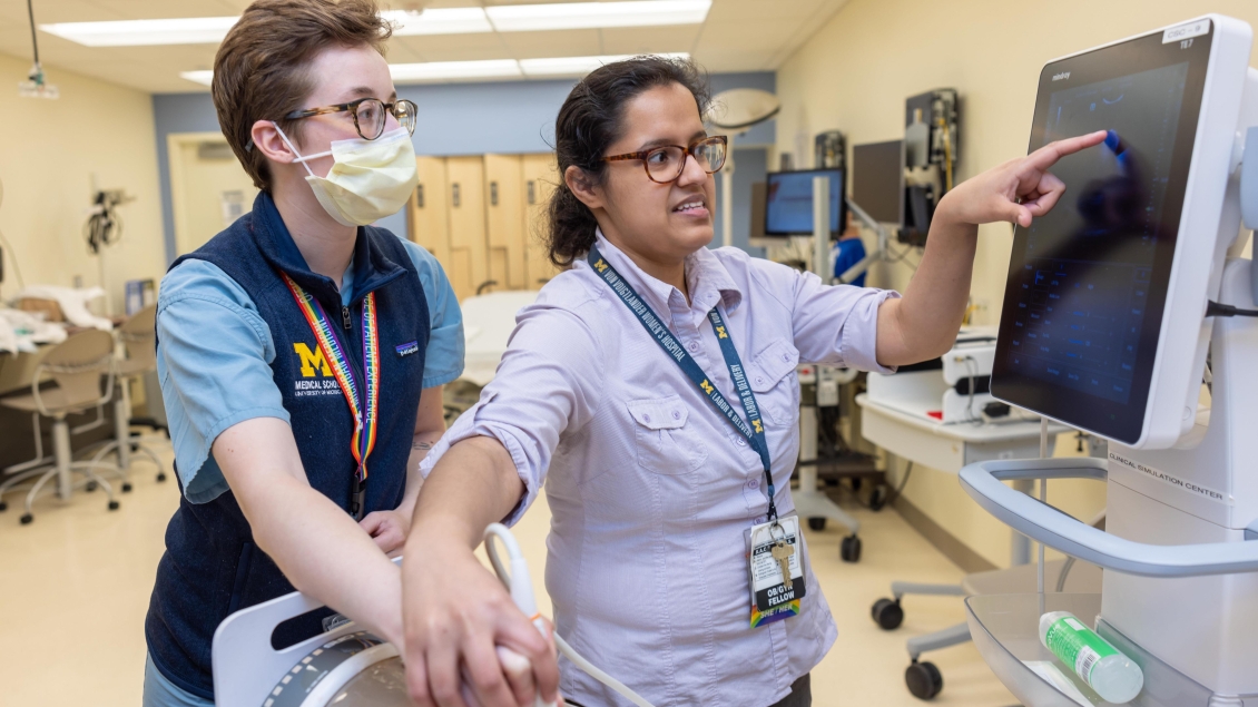  obgyn fellow teaches studuent during lab simulation while showing scans on a monitor 