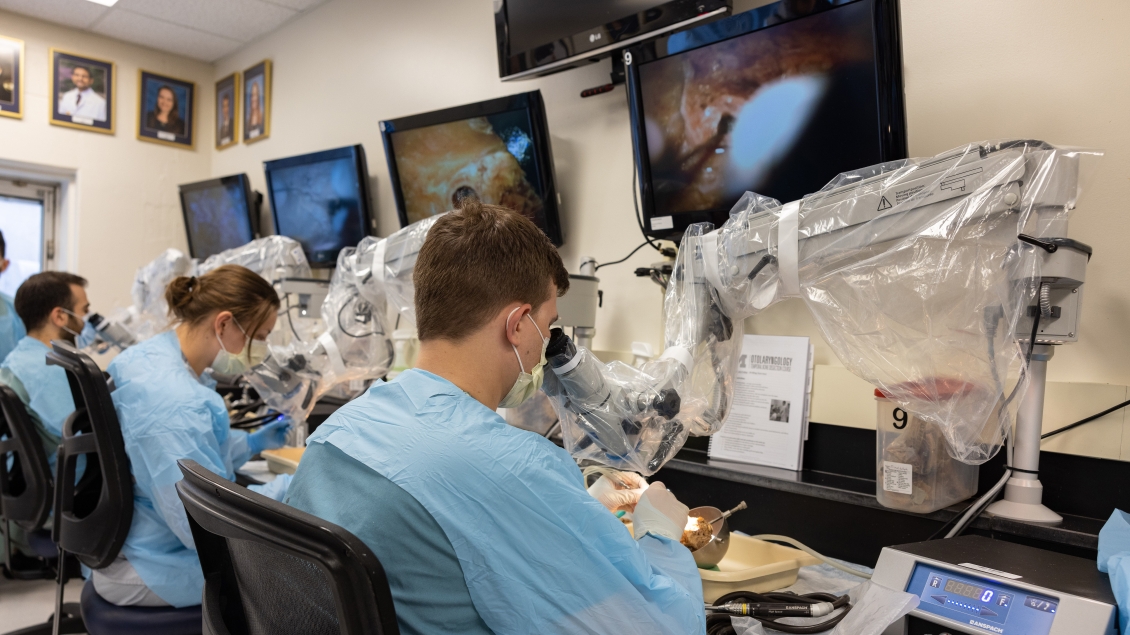 lab trainees practice stitches under a microscope 