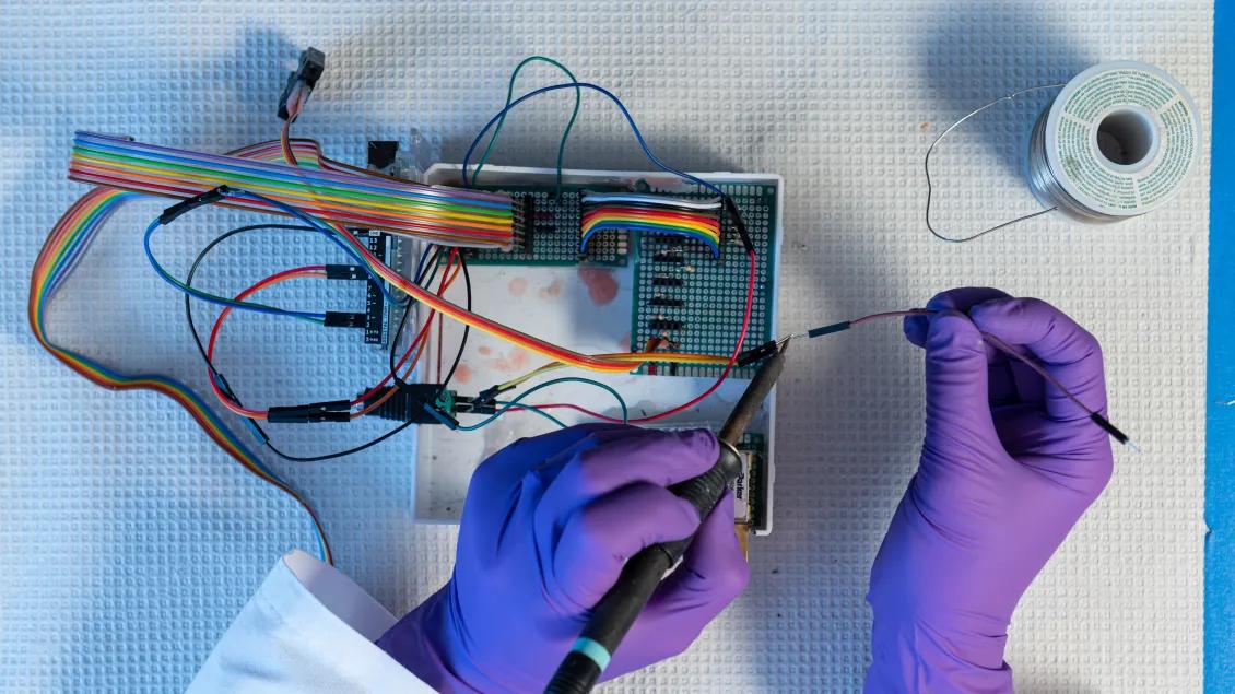 doctor in latex gloves works with wires in a part of a computer chip 