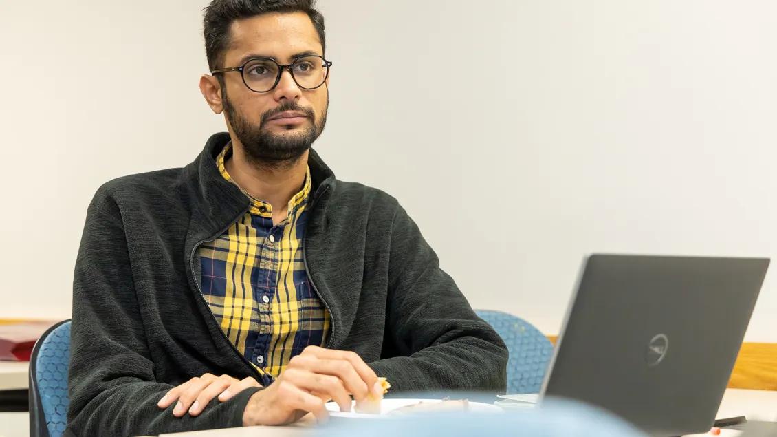 man sitting with computer at desk looking up