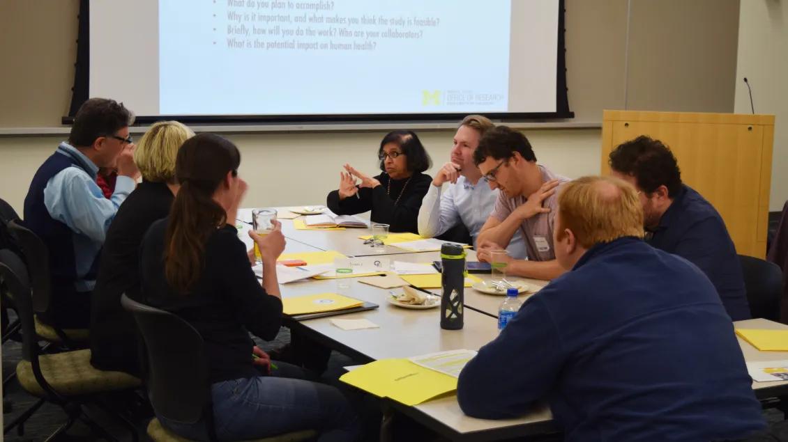 group of researchers talking across table at R01 Boot Camp event