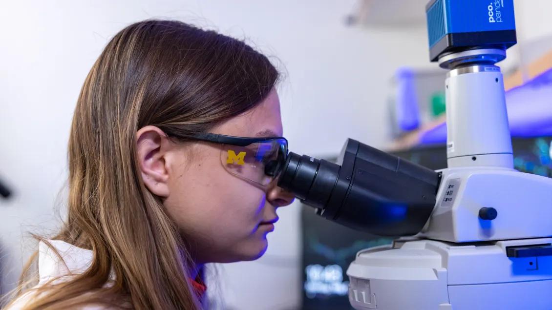 Woman Looks through microscope 