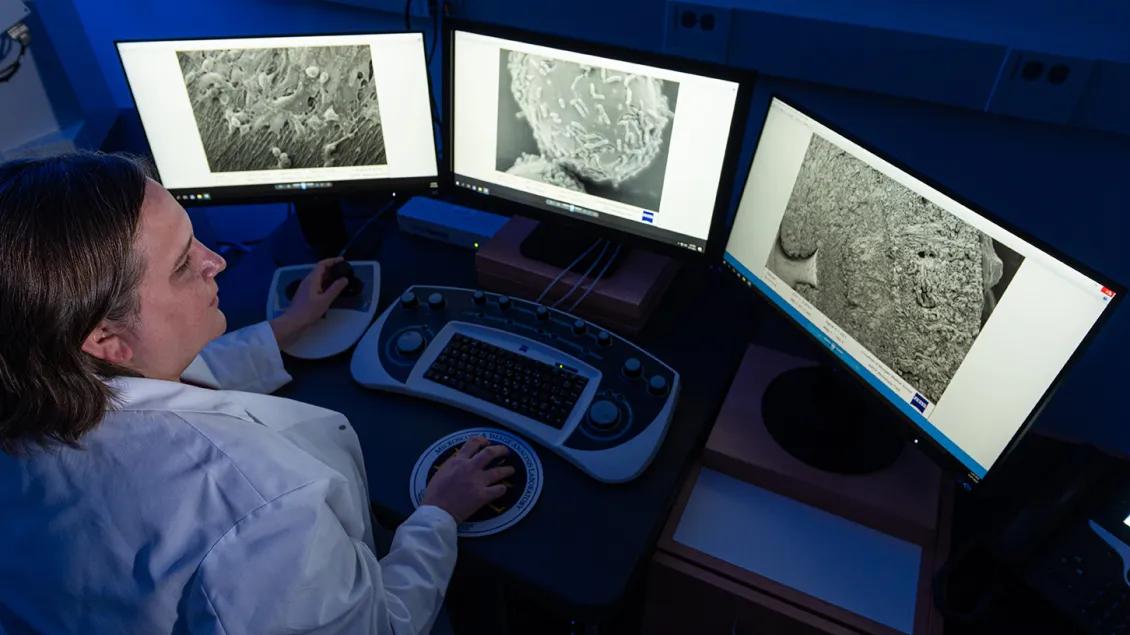 Photo of a researcher in front of computers showing electron microscopy